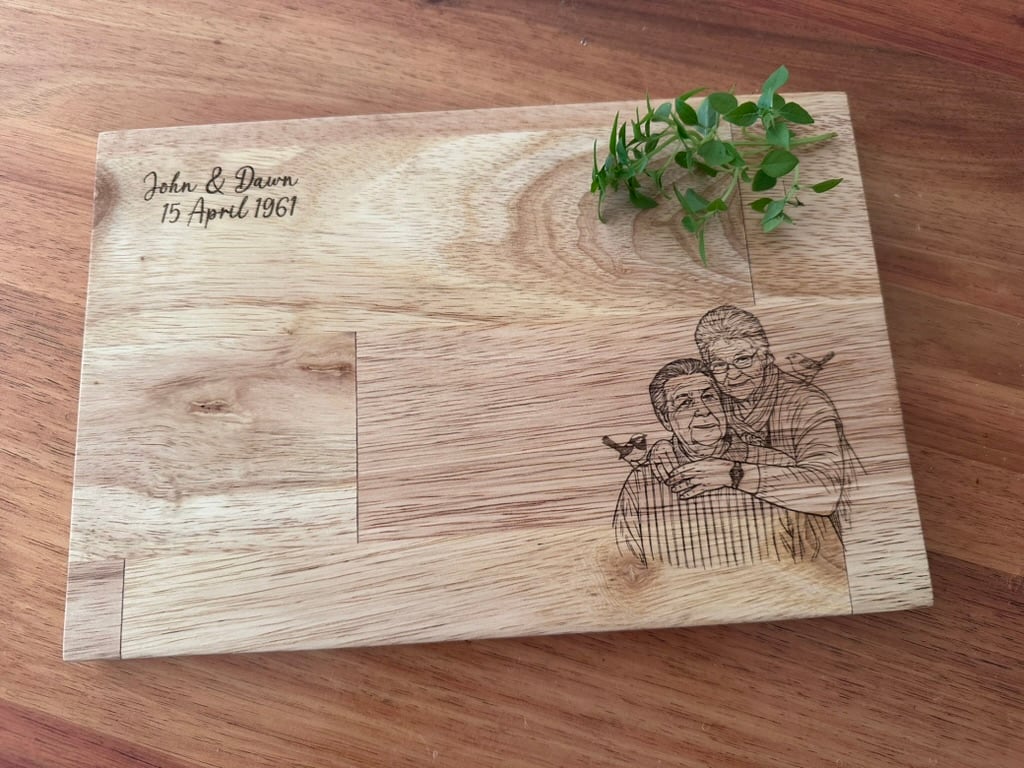 Personalised chopping board engraved with a portrait and styled with green foliage